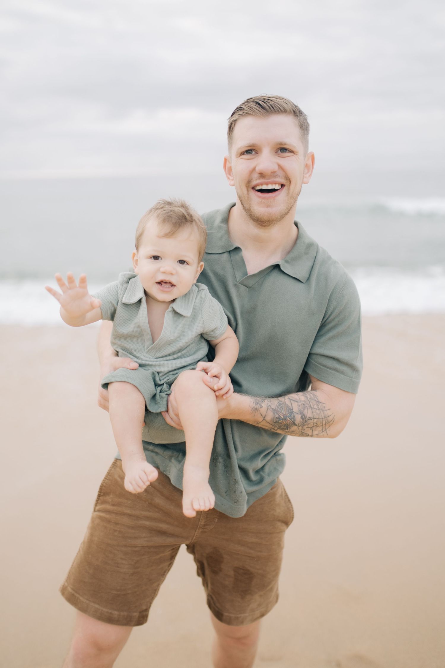 A happy parent and toddler share joyful moments on a sandy beach.