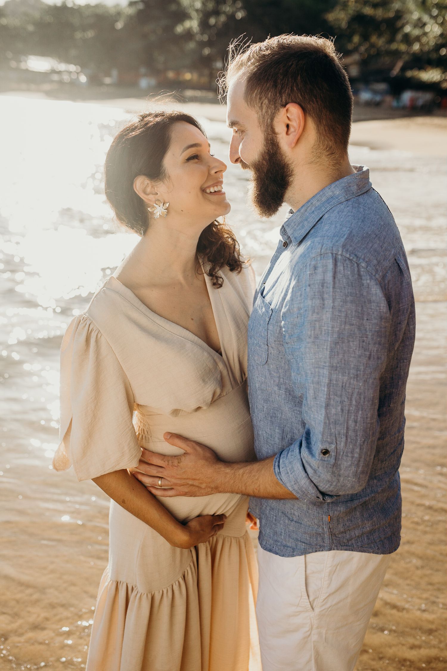 Romantic couple embracing on beach during golden hour sunset.
