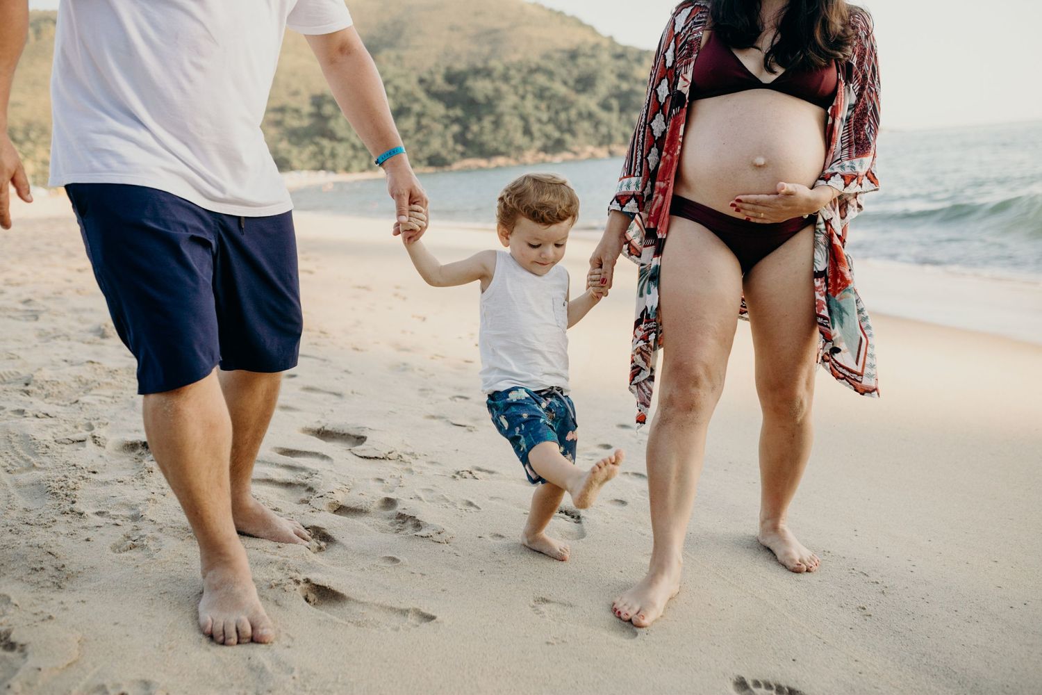 Family enjoying a beach walk together as waves crash on the shore.