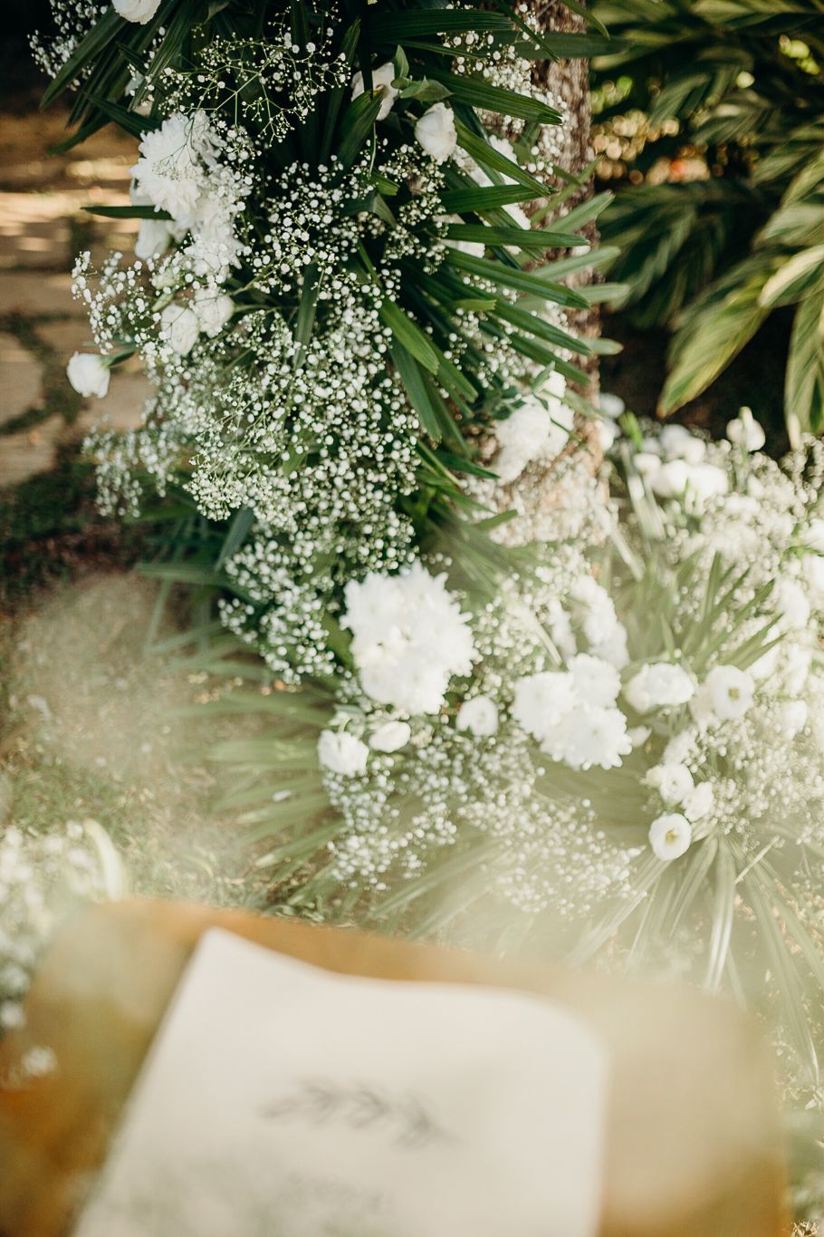 Soft focus floral arrangement featuring baby's breath and white flowers with wedding stationery.