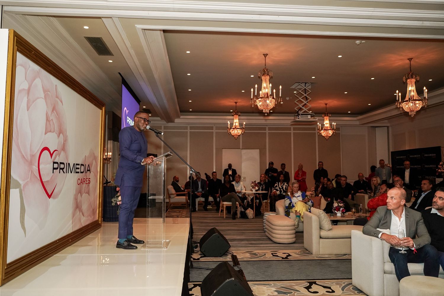 Speaker addressing a seated audience at a Primedia Cares corporate event.