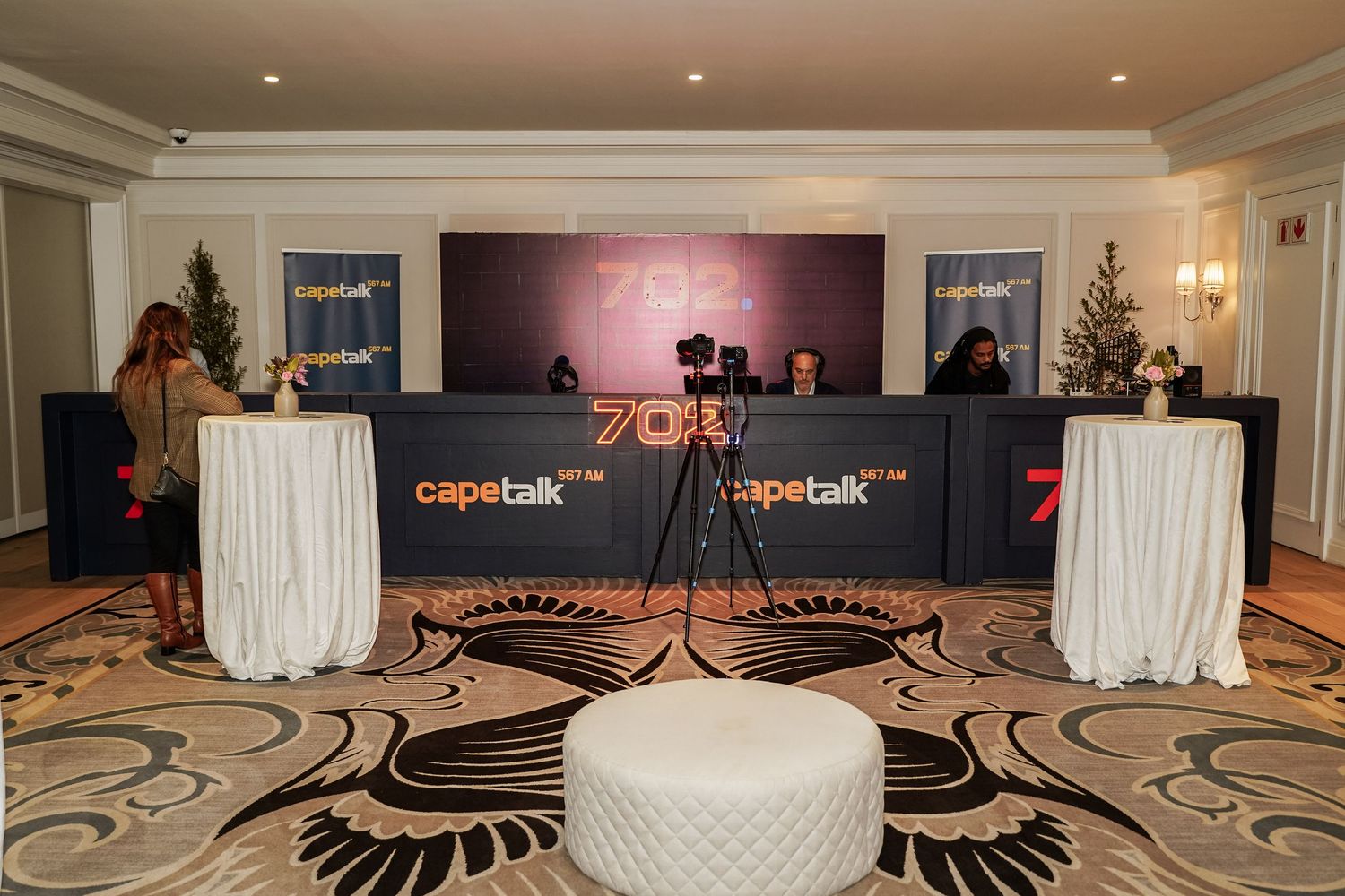702 and Cape Talk branded broadcast desk setup in an elegant hotel ballroom.