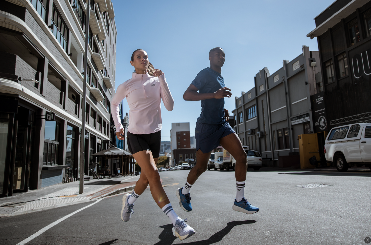 Two men running together on a city street in athletic wear.
