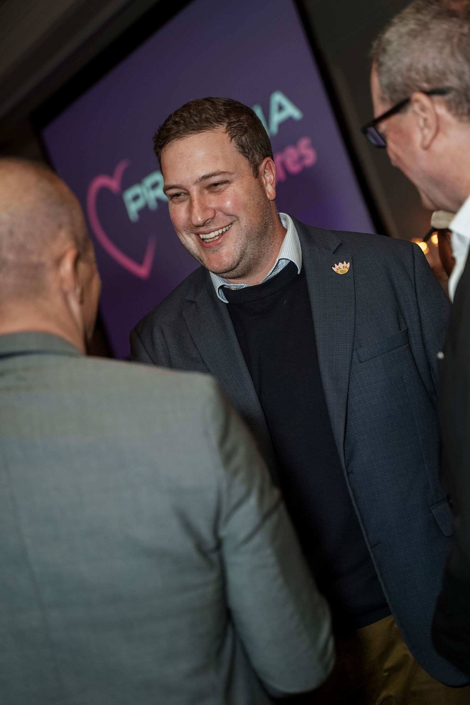 Man in blazer laughing during conversation at Primedia Cares corporate networking event.