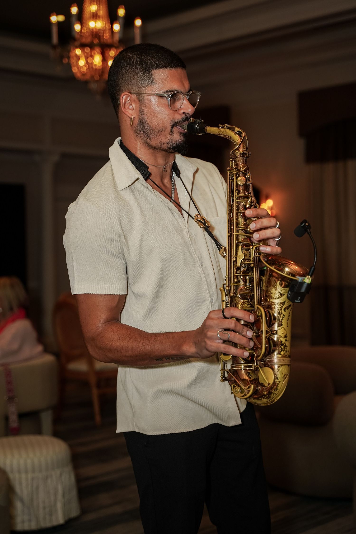Male musician playing saxophone under chandelier at Primedia Cares corporate gala.