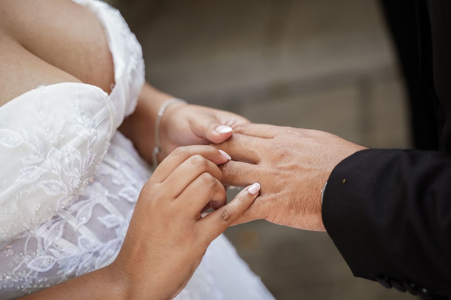 Groom placing wedding ring on bride's finger during ring exchange ceremony close-up detail shot.
