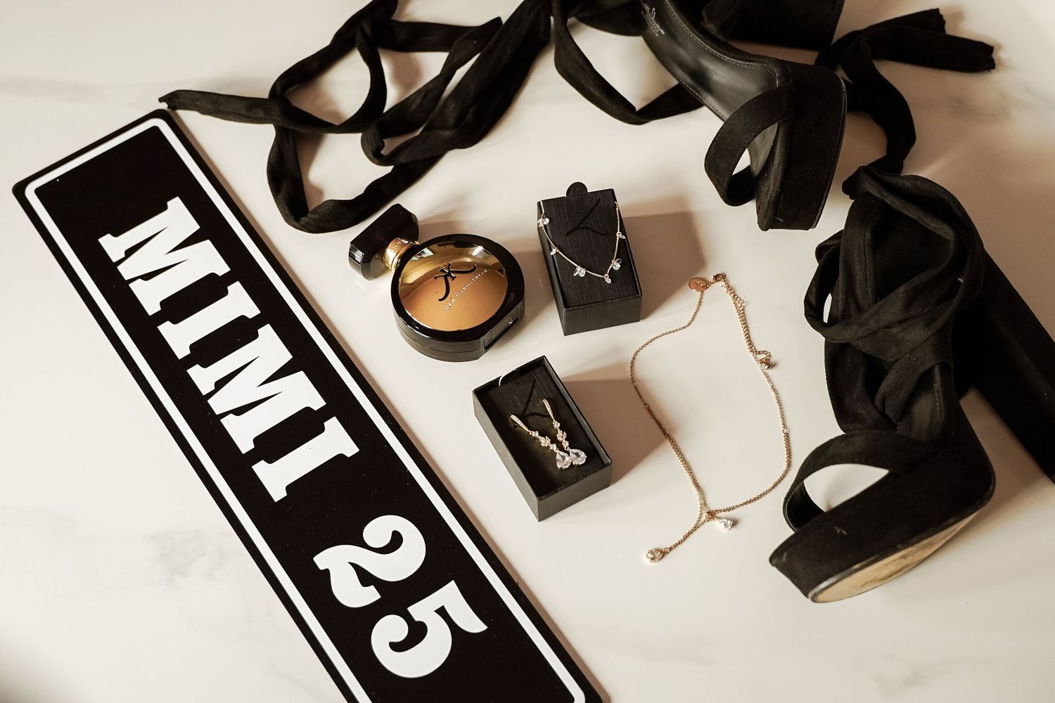 Prom accessories flat lay with MIMI 25 sign, jewelry, and black heels.