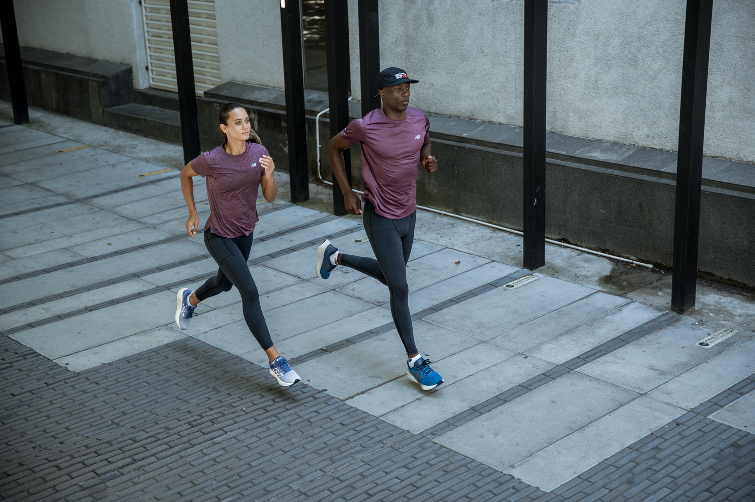 Man and woman running together in matching athletic wear on a city street.