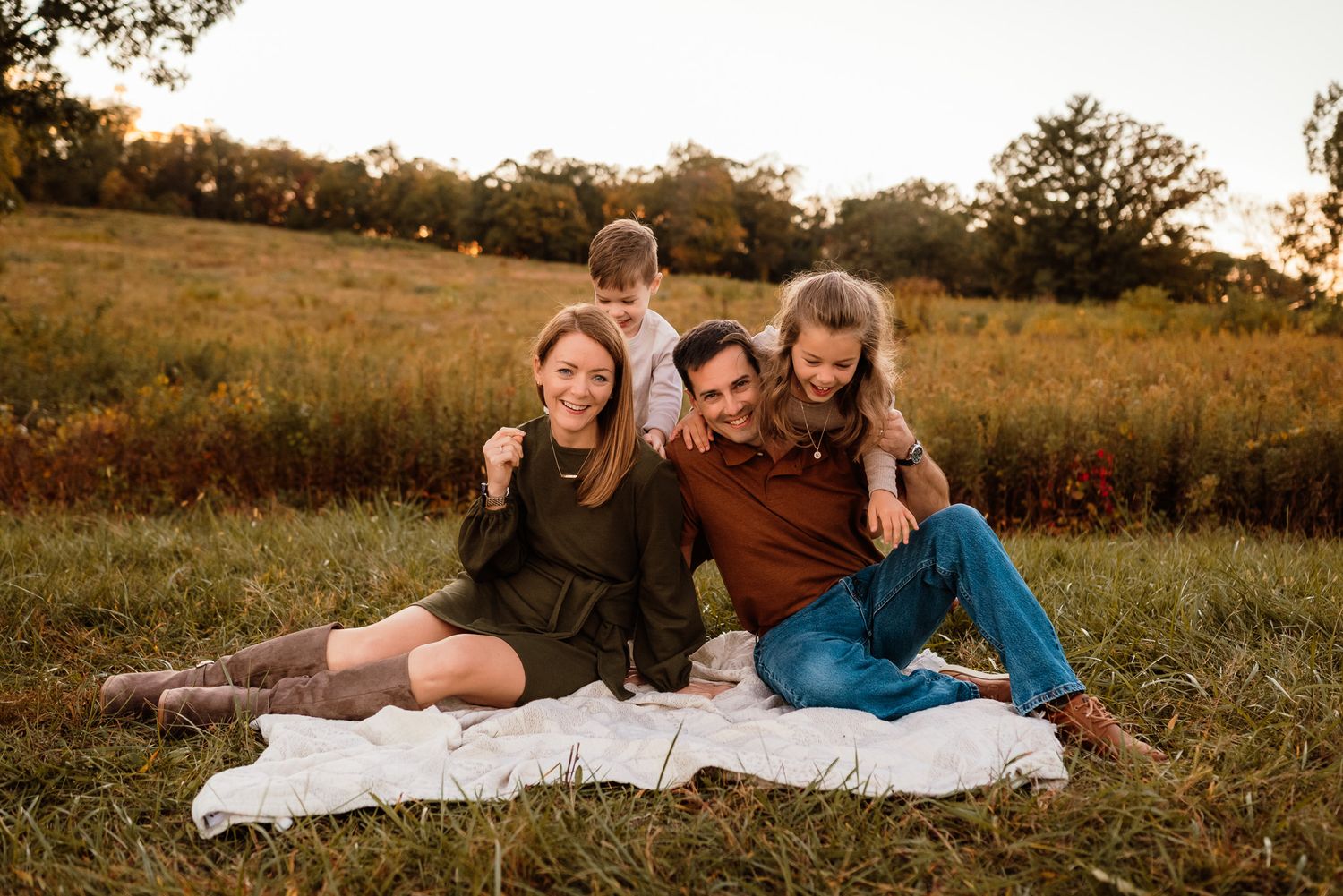 Family of four cuddling on blanket in grass, lifestyle family photography, Collegeville PA