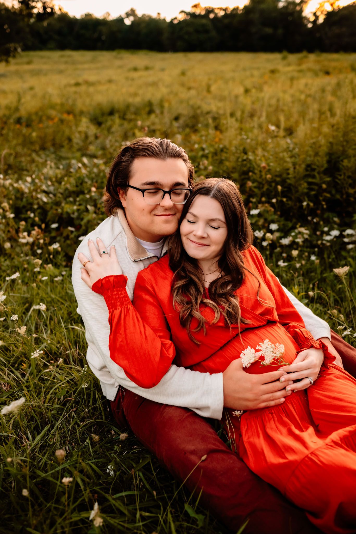 Pregnant woman holding belly in sunlit field, outdoor maternity session, Phoenixville PA