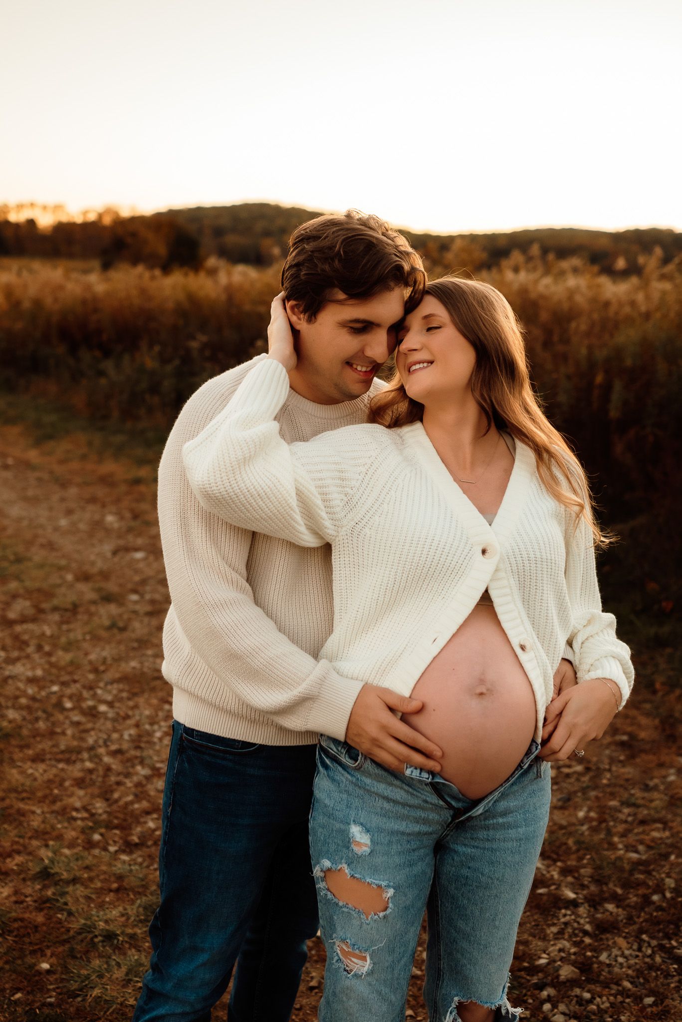 Couple kissing during maternity portraits, golden hour photography, Collegeville PA