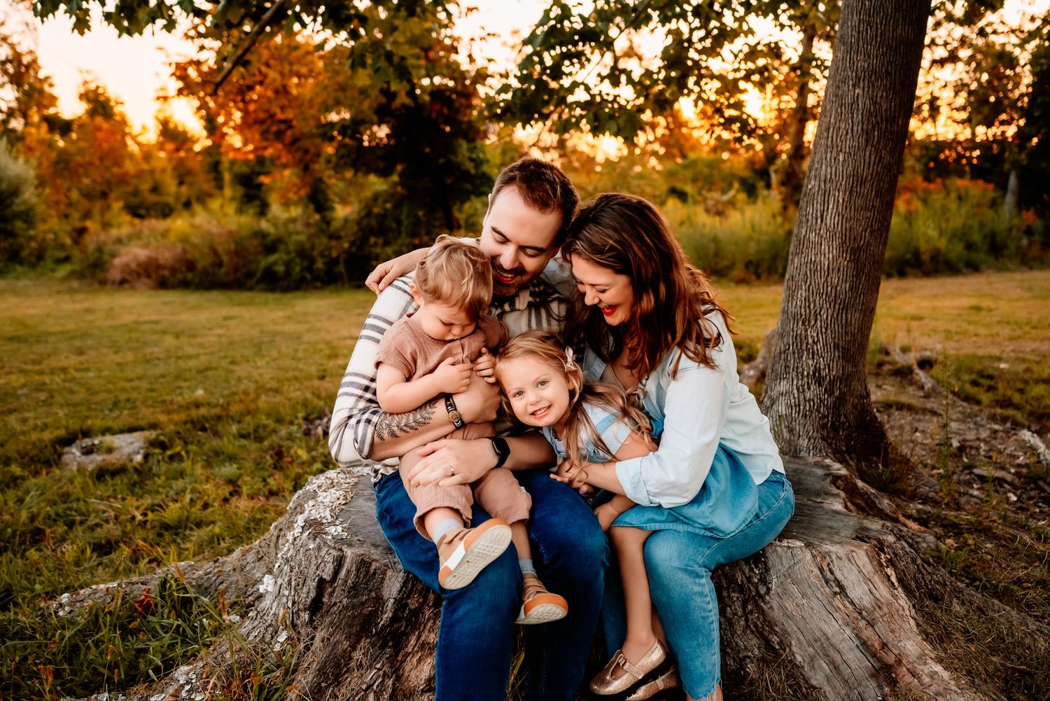 Family of four cuddling on blanket in grass, lifestyle family photography, Collegeville PA