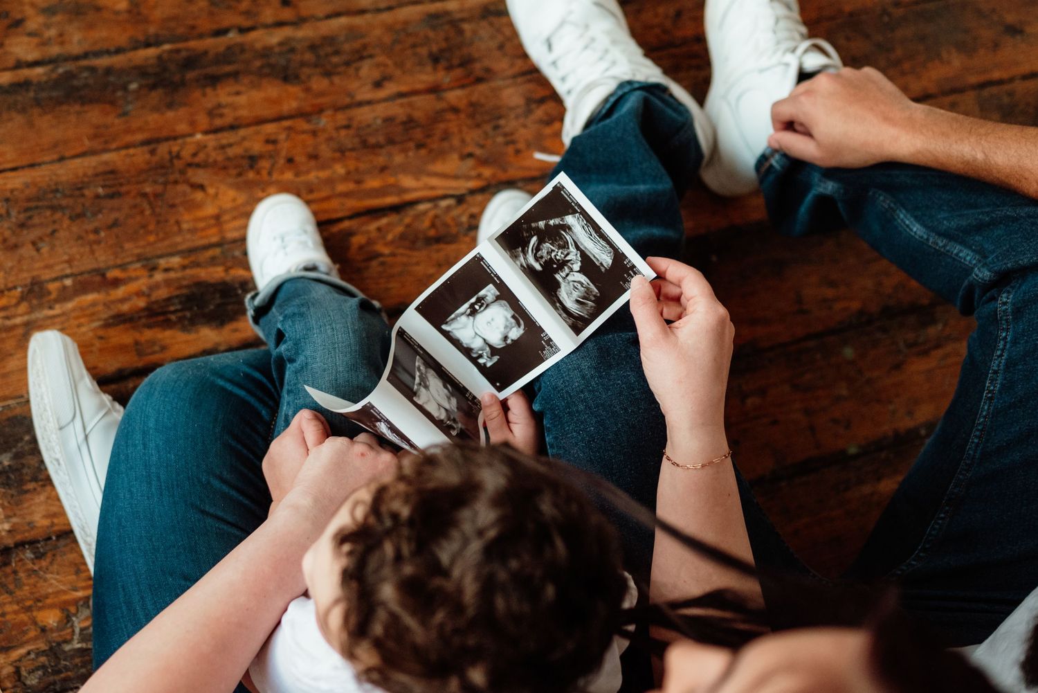 Couple and toddler holding an ultrasound photo in a cozy studio in Phoenixville, PA