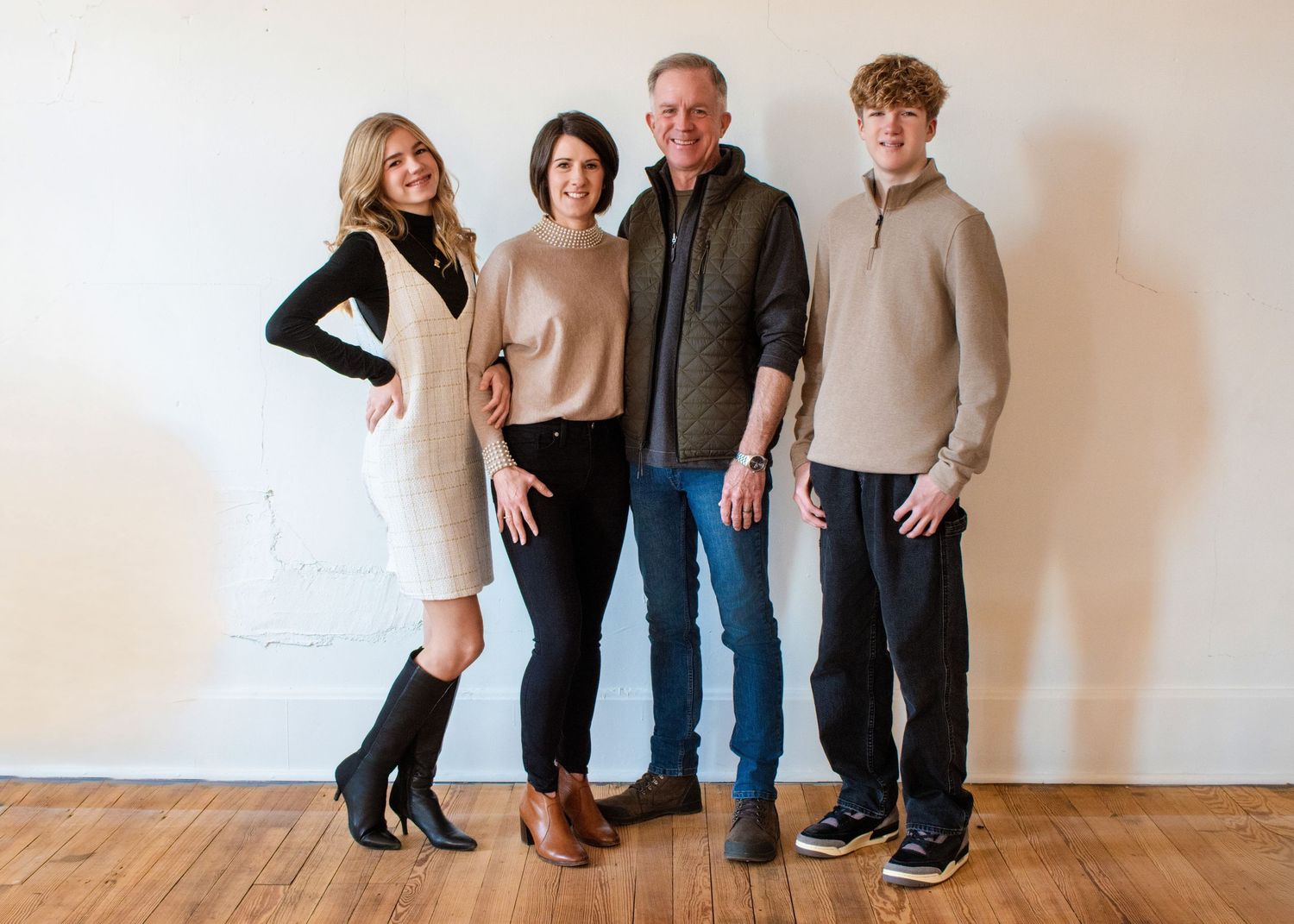 A group of people in casual attire pose together against a white wall in a progression of different positions.
