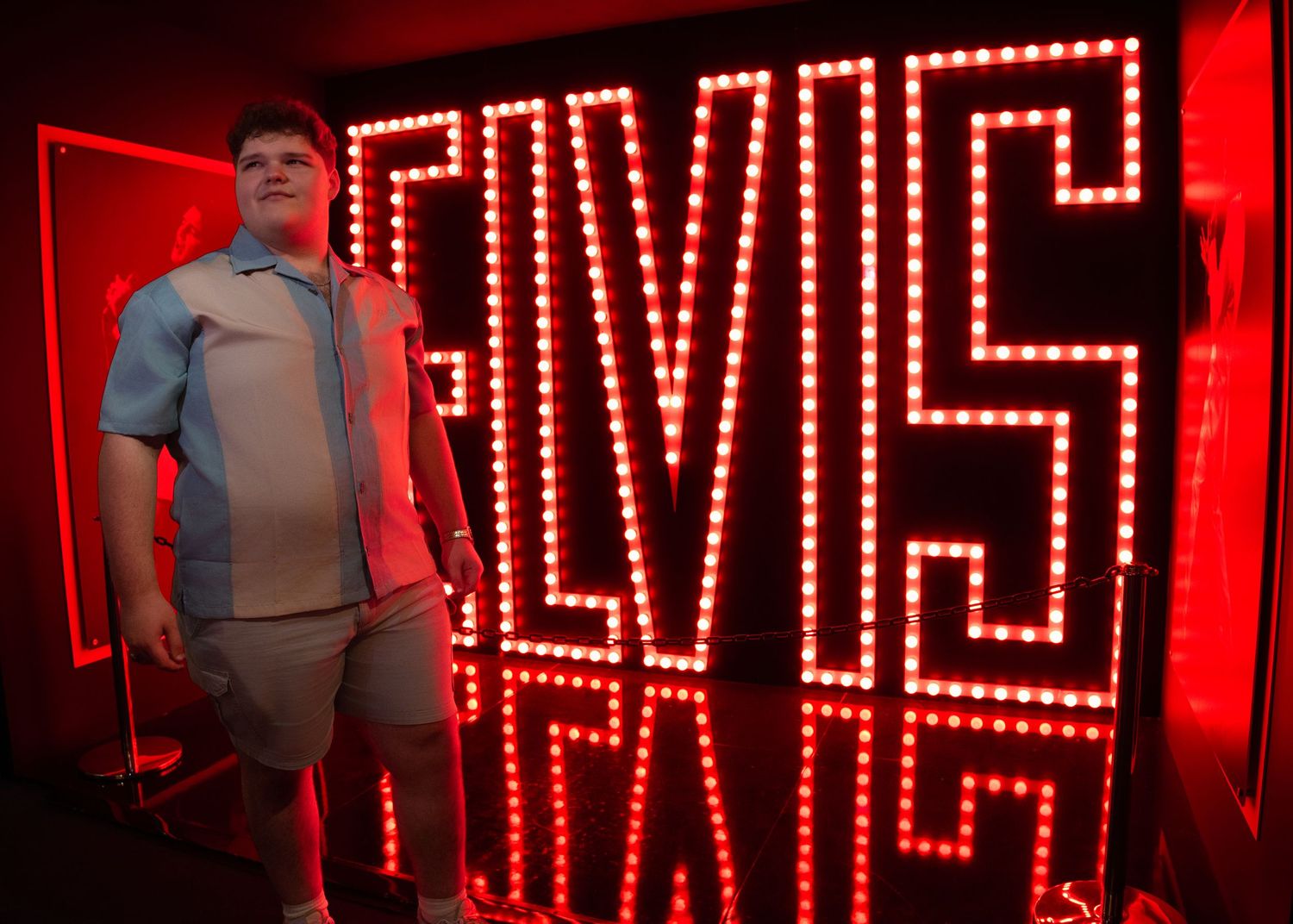 A person stands next to a large illuminated red neon 
