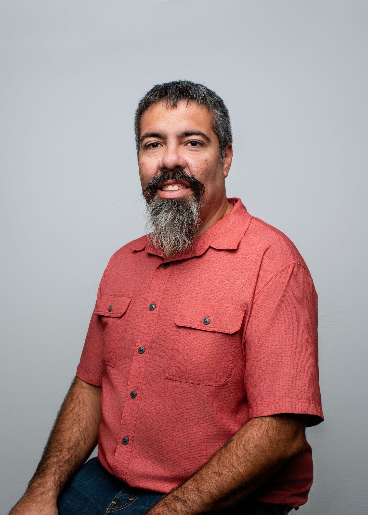 Portrait series of someone in a coral button-up shirt against a light gray background.