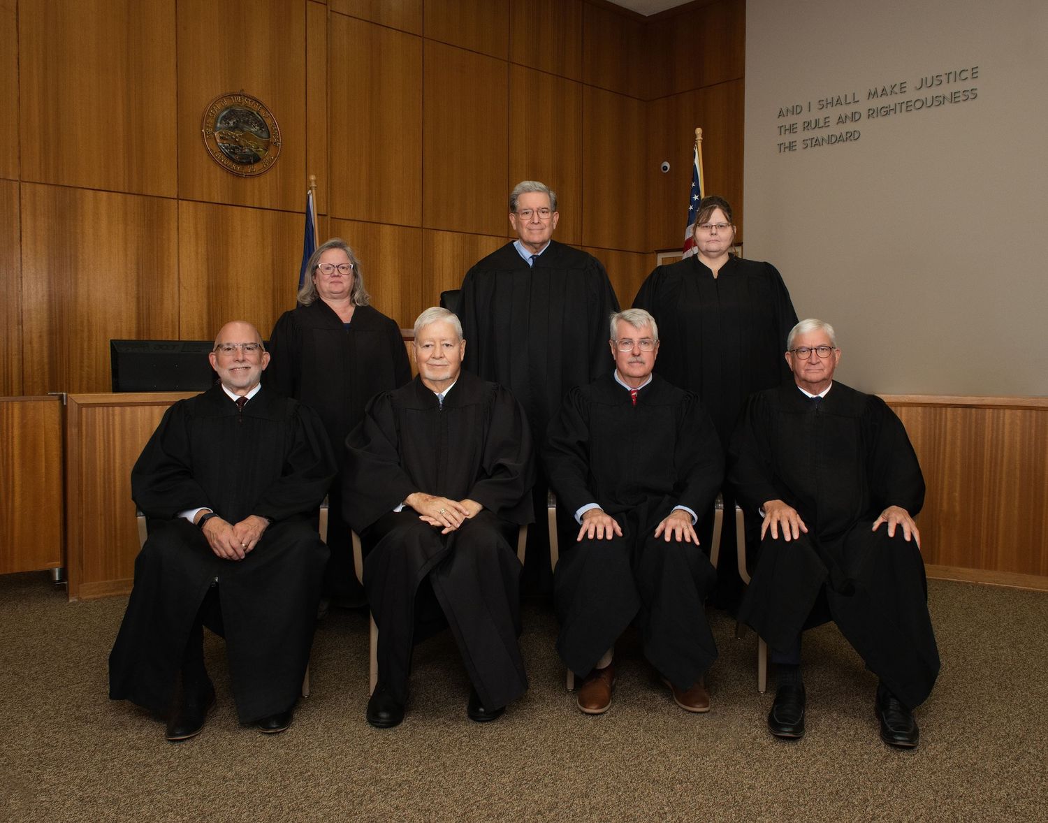 A row of judges in black robes seated on a bench in a wood-paneled courtroom.