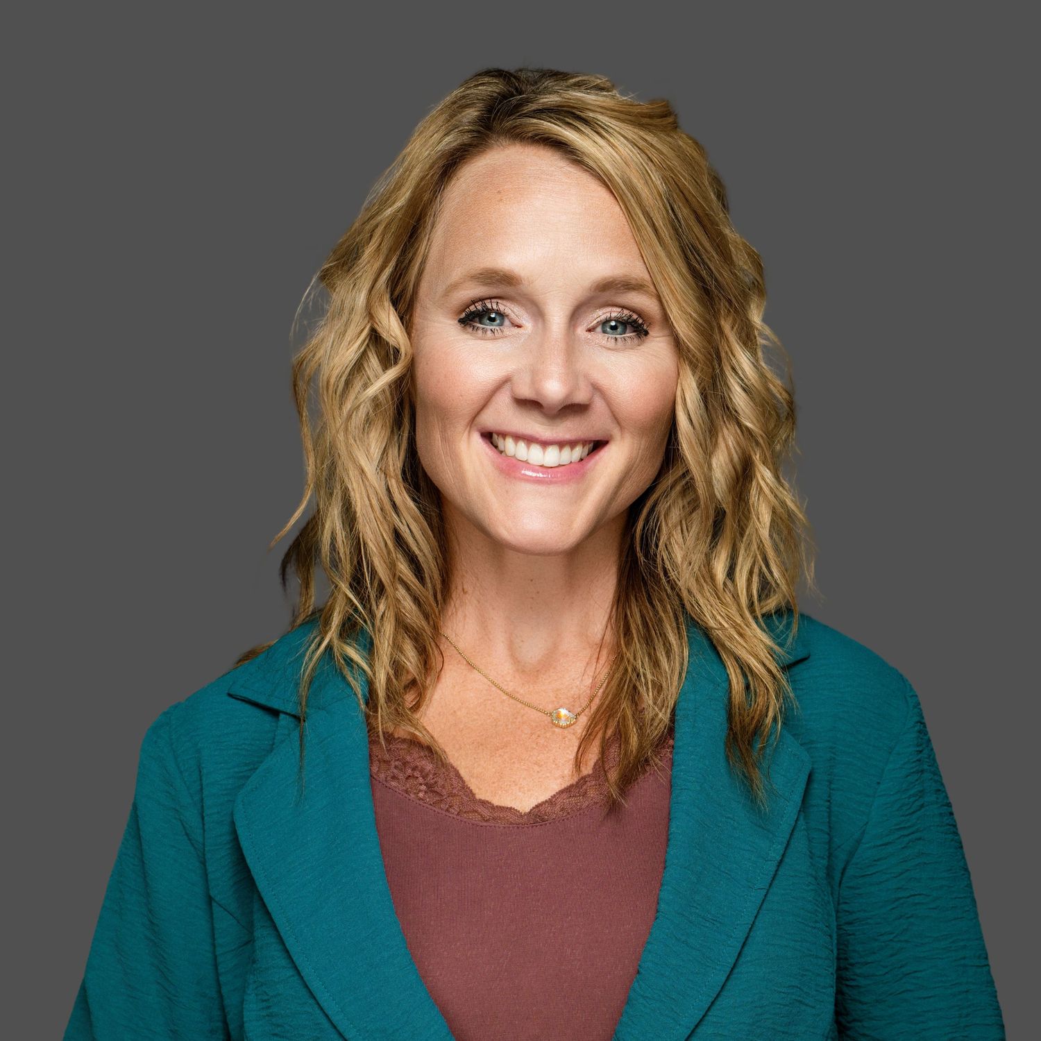 Studio portraits featuring someone in a teal blazer and burgundy top against a dark background.