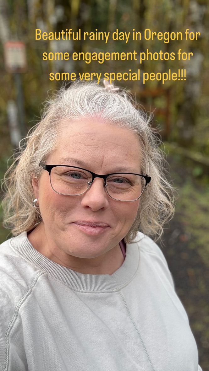A photographer in Oregon on a rainy day wearing glasses and a light gray sweatshirt smiles at the camera.