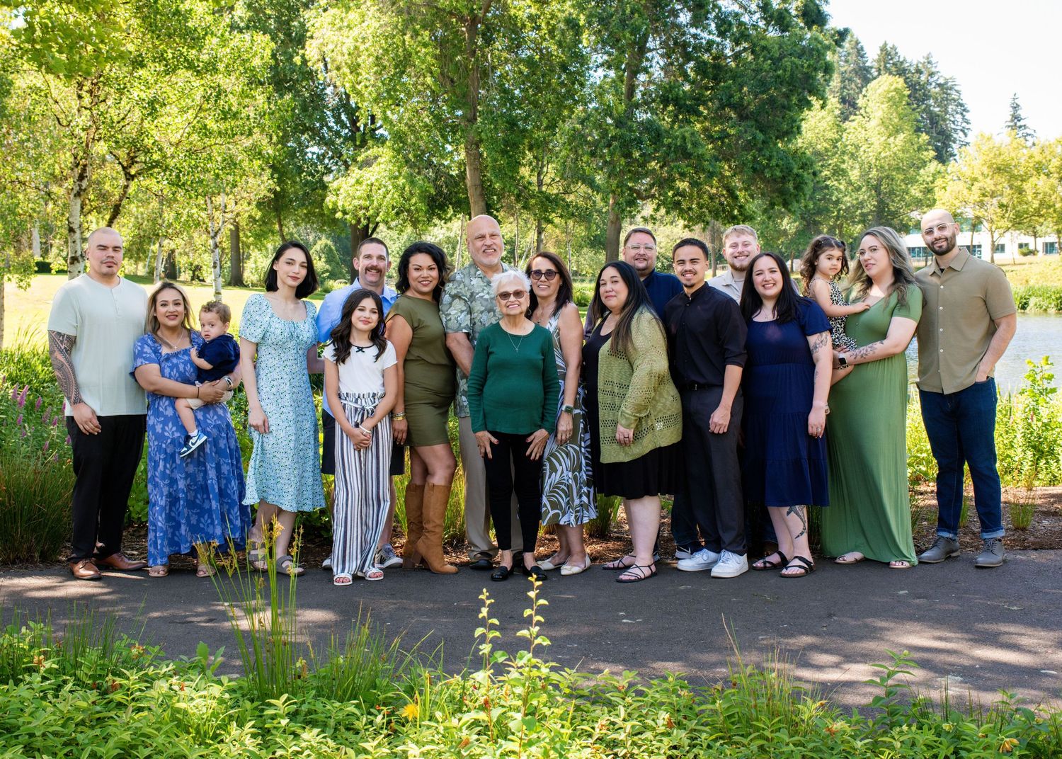 Extended family gathering photographed in lush green park setting.