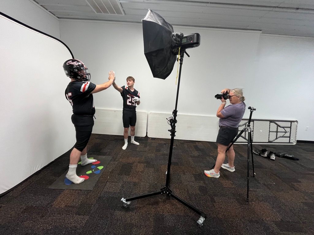 Photography studio setup showing people working with equipment on dark flooring.