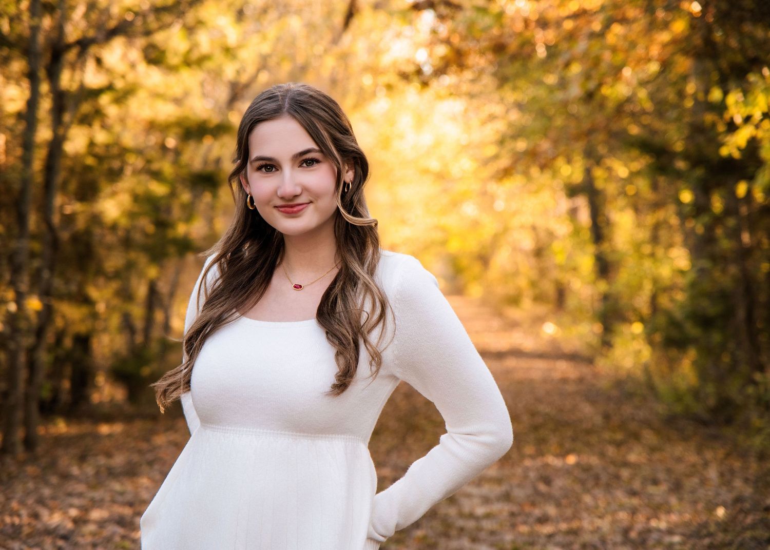 Portrait photo in autumn forest with golden bokeh background and warm sunlight filtering through fall foliage.