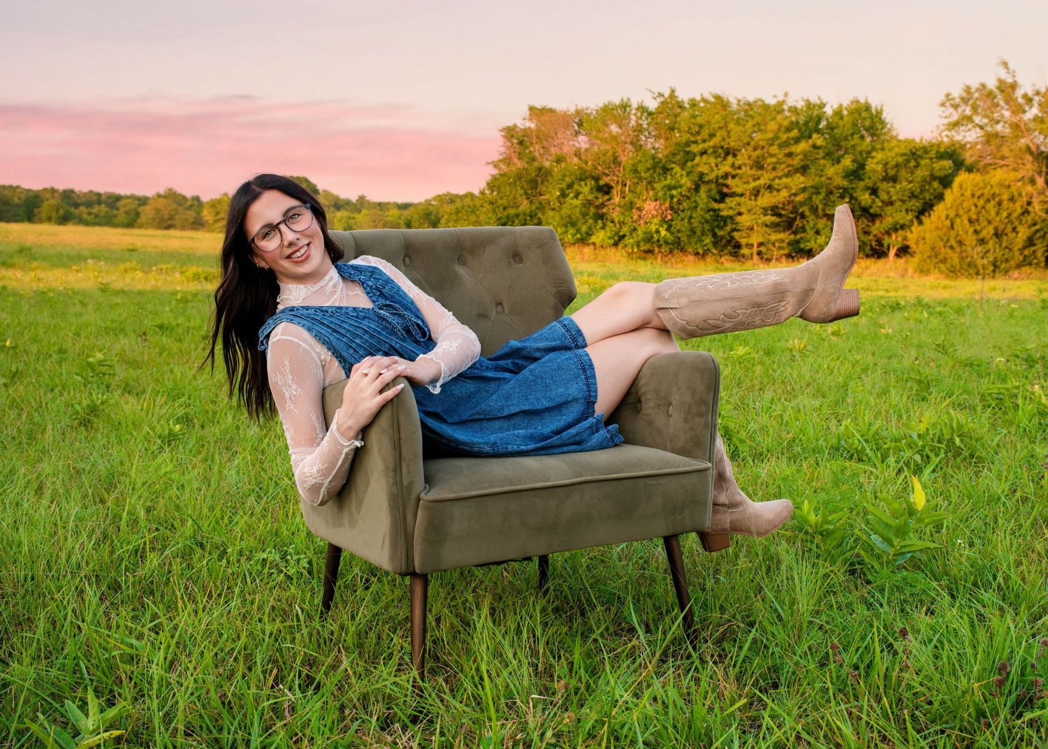 High school senior portrait in Kansas featuring a relaxed, confident senior photographed in natural light, in a meadow, with a pink sunset.
