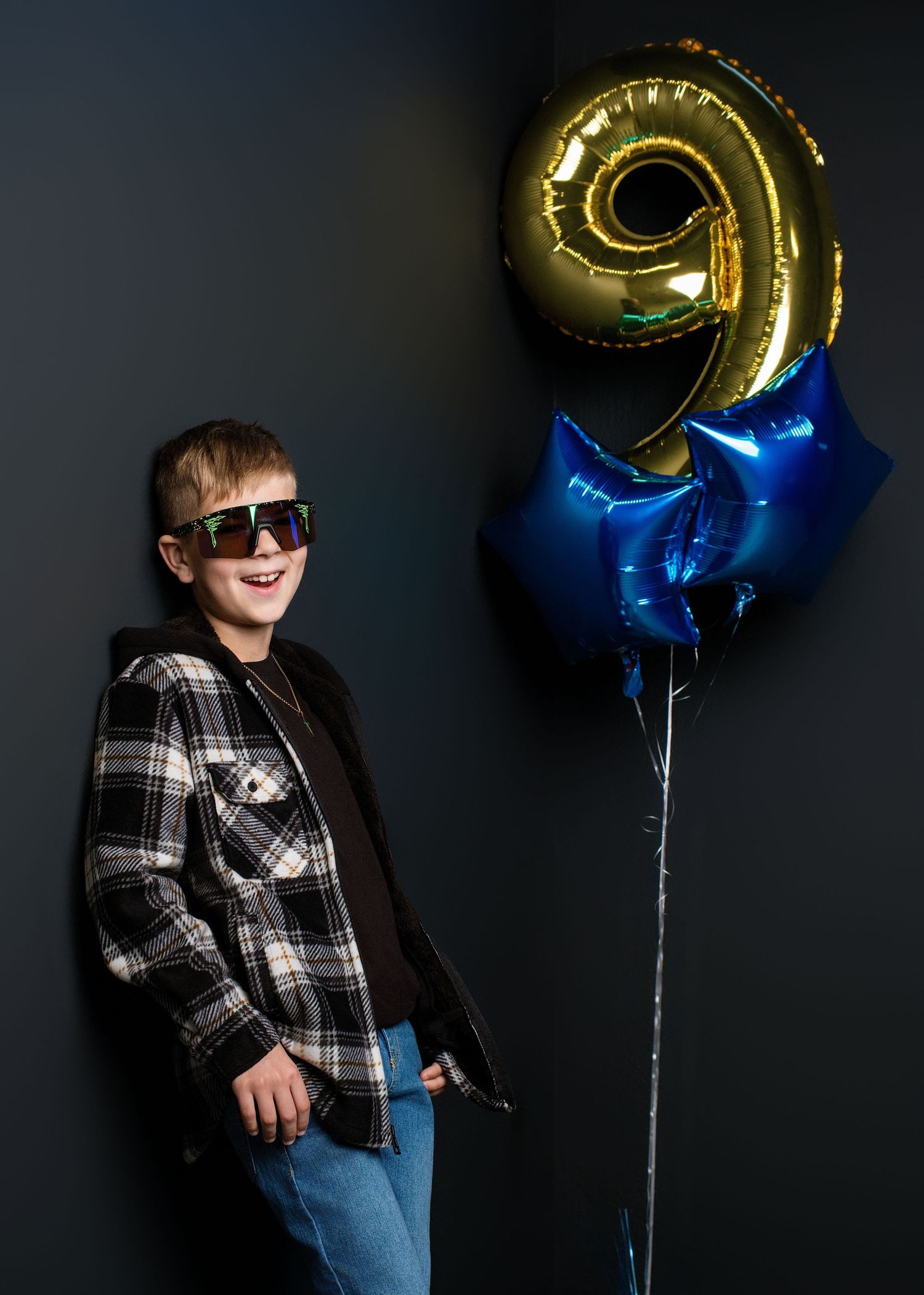 Birthday themed photoshoot with gold number balloons against a dark background.