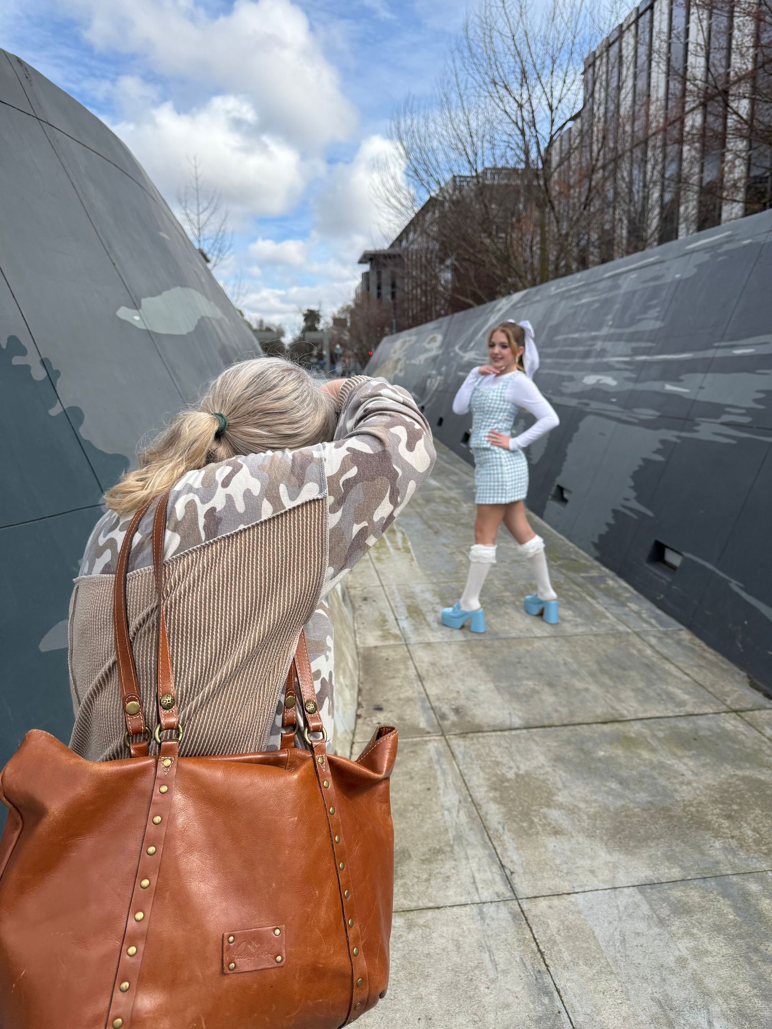 A sequence showing a brown leather handbag being tossed and flipping through the air against a concrete backdrop.