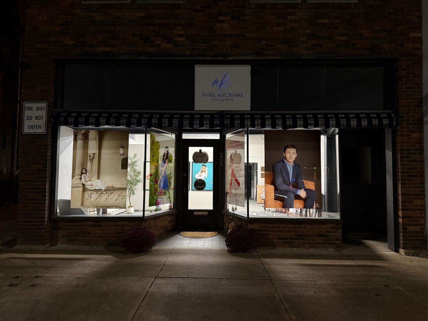 Illuminated boutique clothing store front at night with display windows showcasing fashion mannequins and apparel.