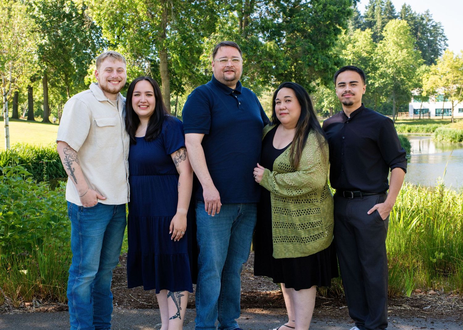 Large family group poses together outdoors in front of green foliage.