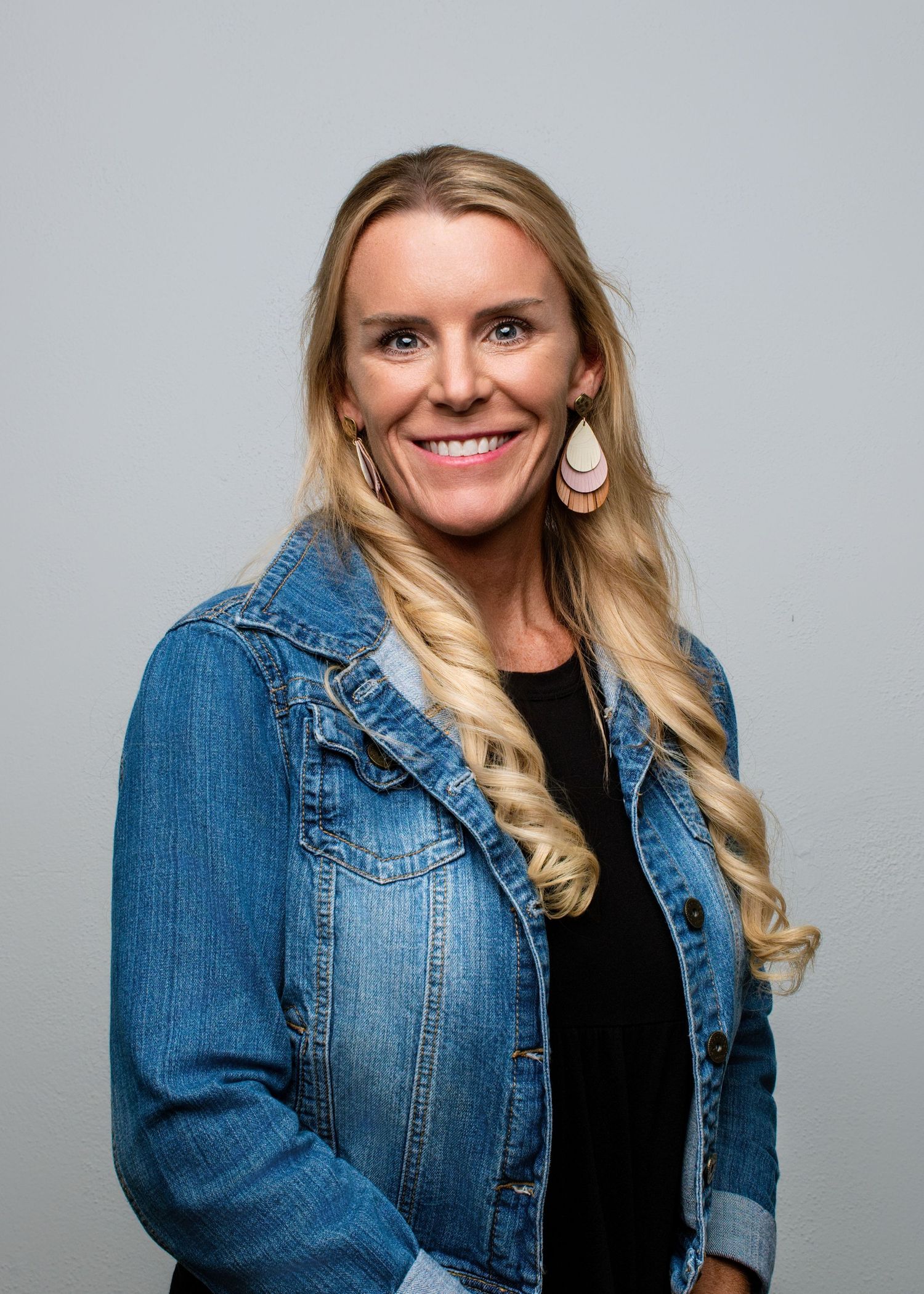 Portrait series of someone wearing a denim jacket and black top against gray background.