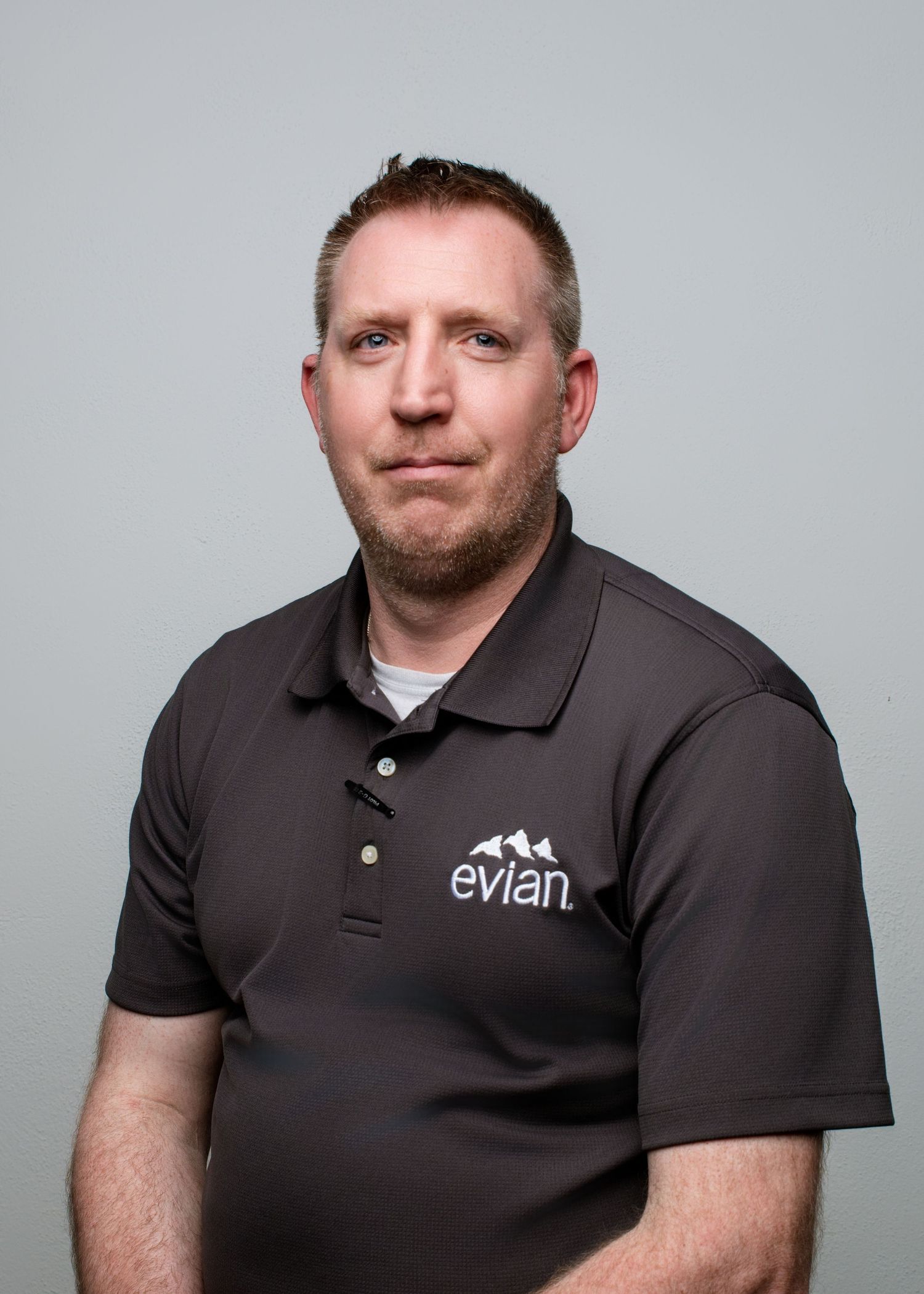 Professional headshots of someone wearing a black Evian polo shirt against gray background.