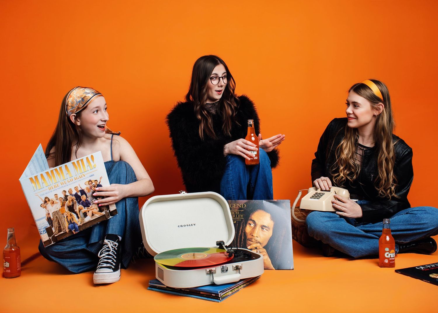 Students sitting at a table with laptops and drinks against vibrant orange background in progressive sequence.