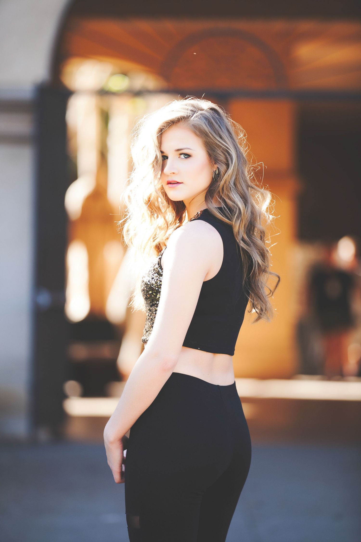 Fashion portrait series in black dress against warm indoor lighting.