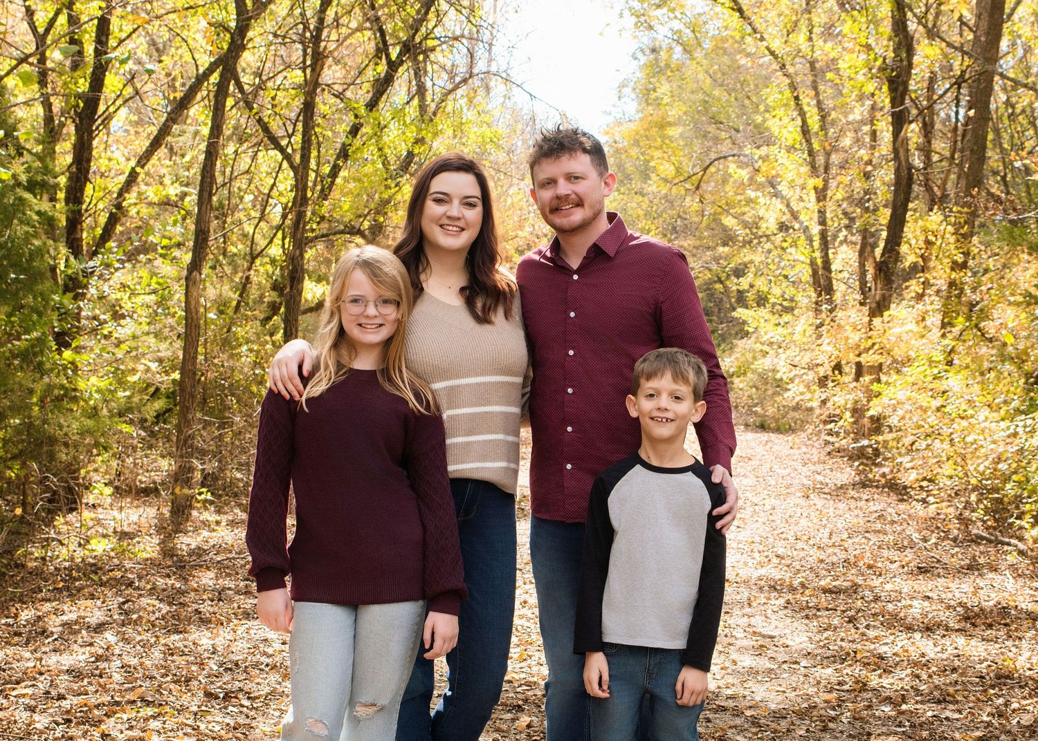 Casual outdoor family photos taken on a tree-lined path during fall season.