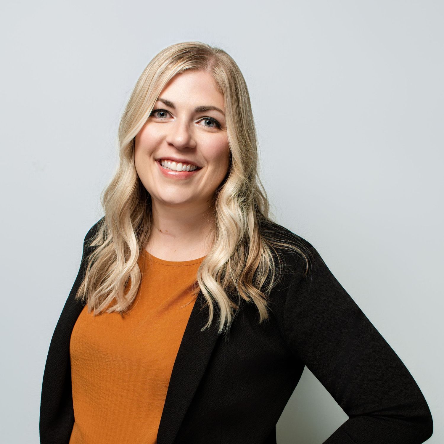 Professional headshots showing someone in an orange top and black blazer.