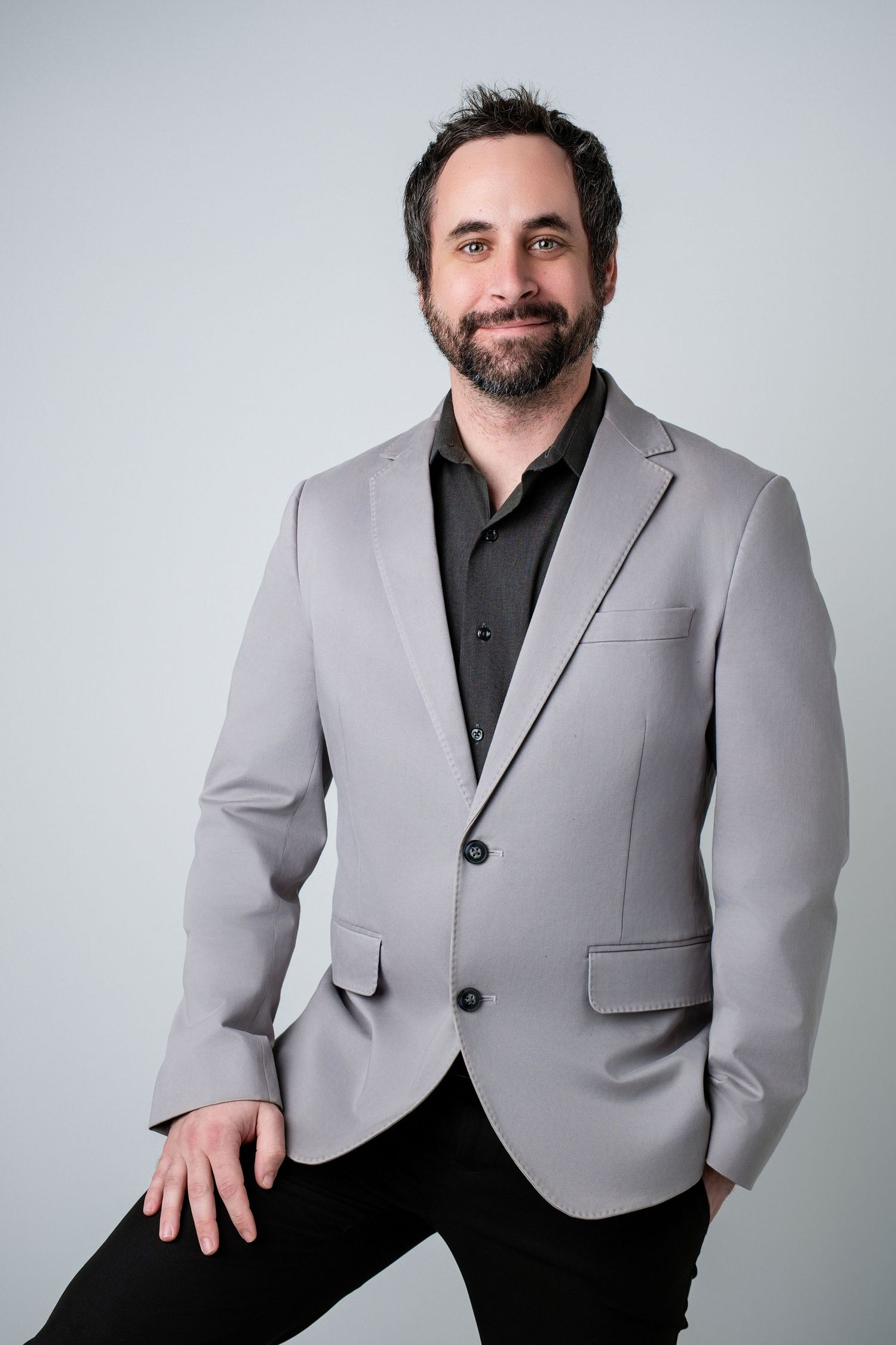 Studio portraits of a person in a light gray blazer posing against a white backdrop.
