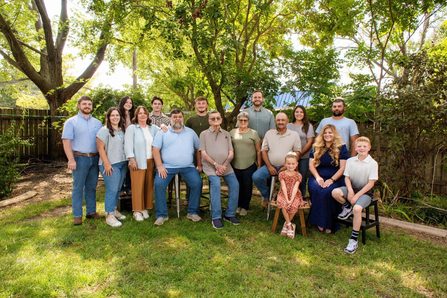 Large family group portrait taken outdoors with natural greenery backdrop.