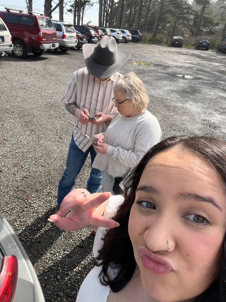 People gathered in a parking lot on an overcast day examining something in their hands.
