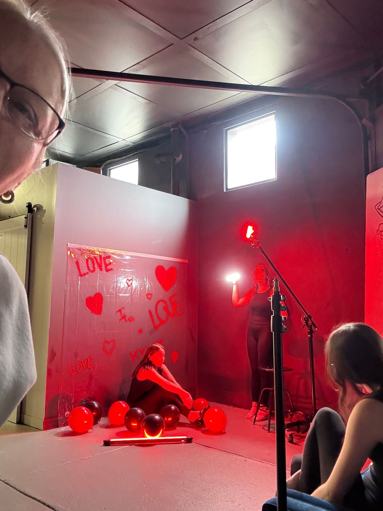 A photography studio setup with red lighting and heart decorations creating a romantic Valentine's Day atmosphere.