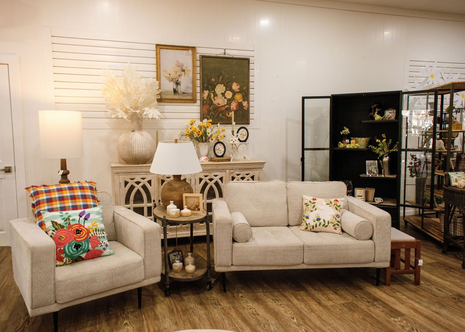 A panoramic view of a modern basement living room with white furniture and wood flooring.