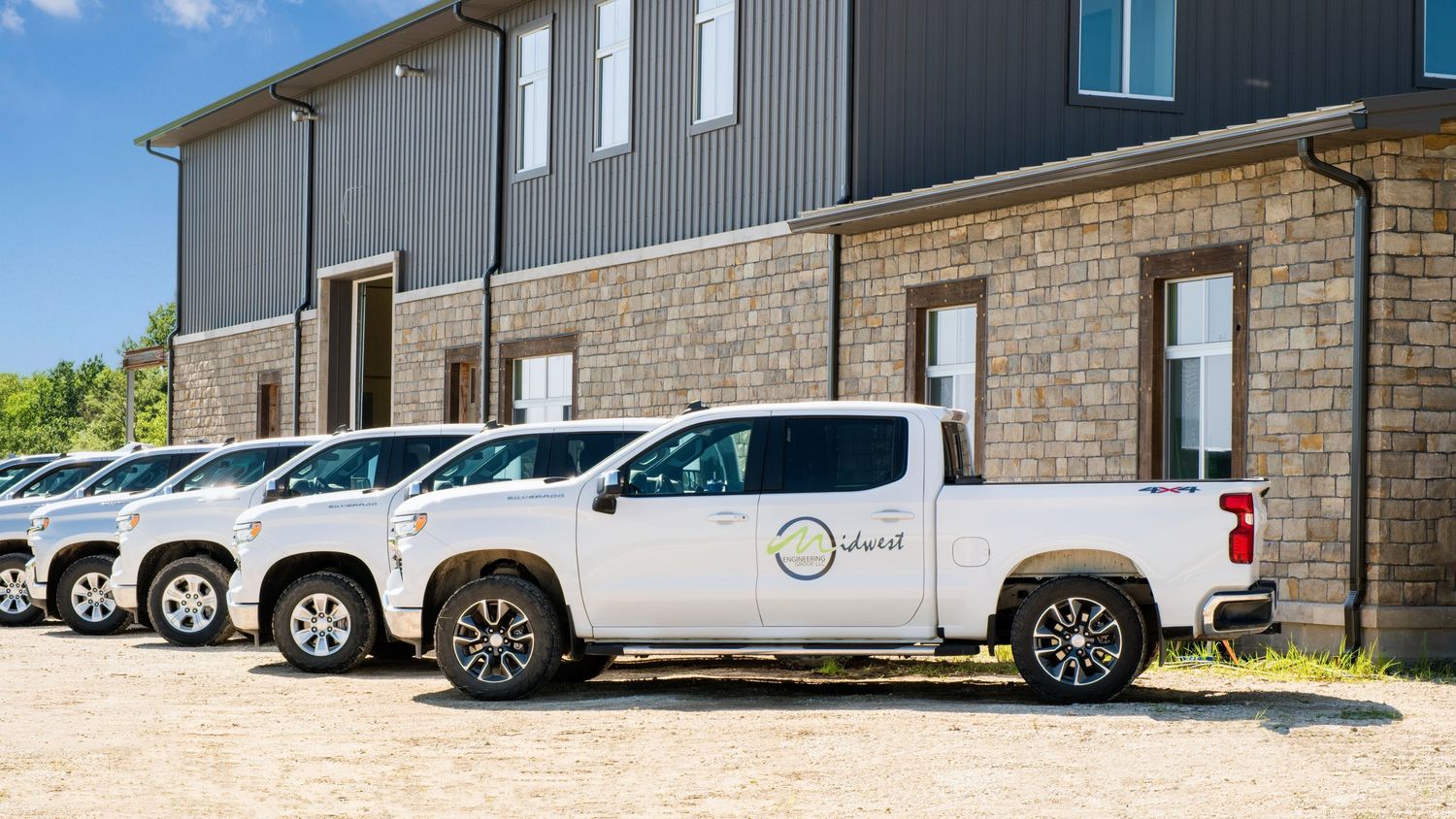 Row of white commercial vehicles parked outside industrial building.