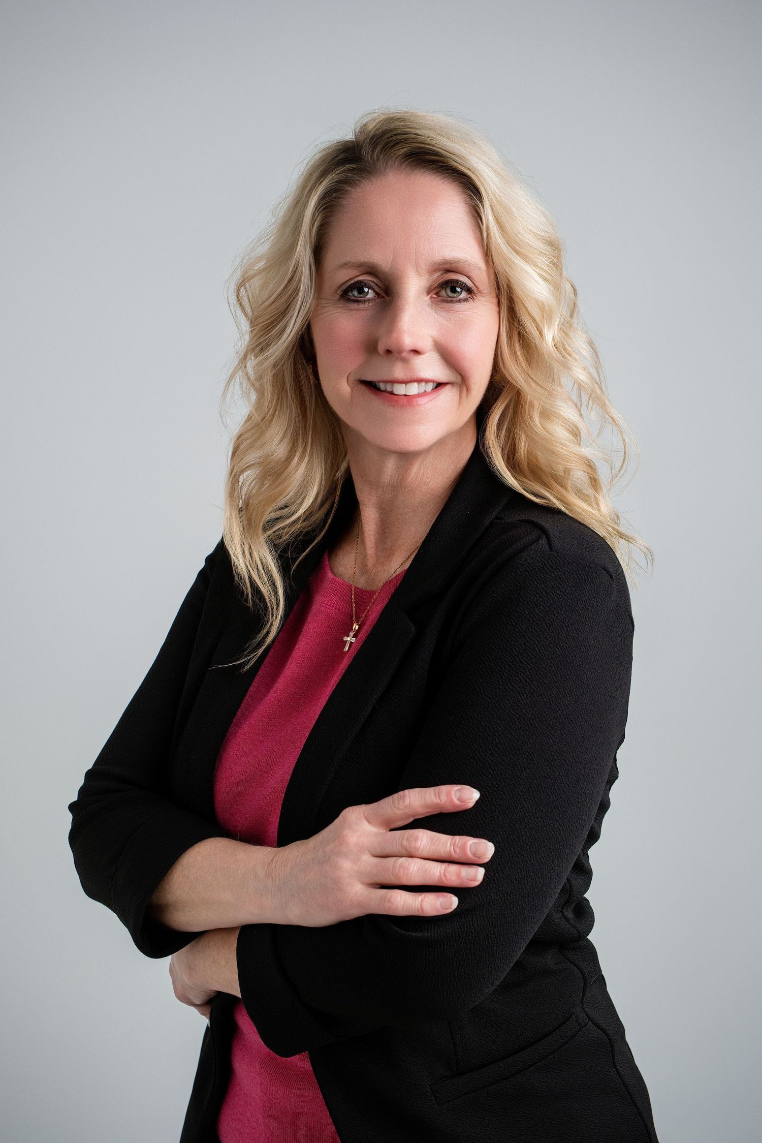 Professional headshot series showing someone in a black blazer and pink top with warm expressions against gray background.