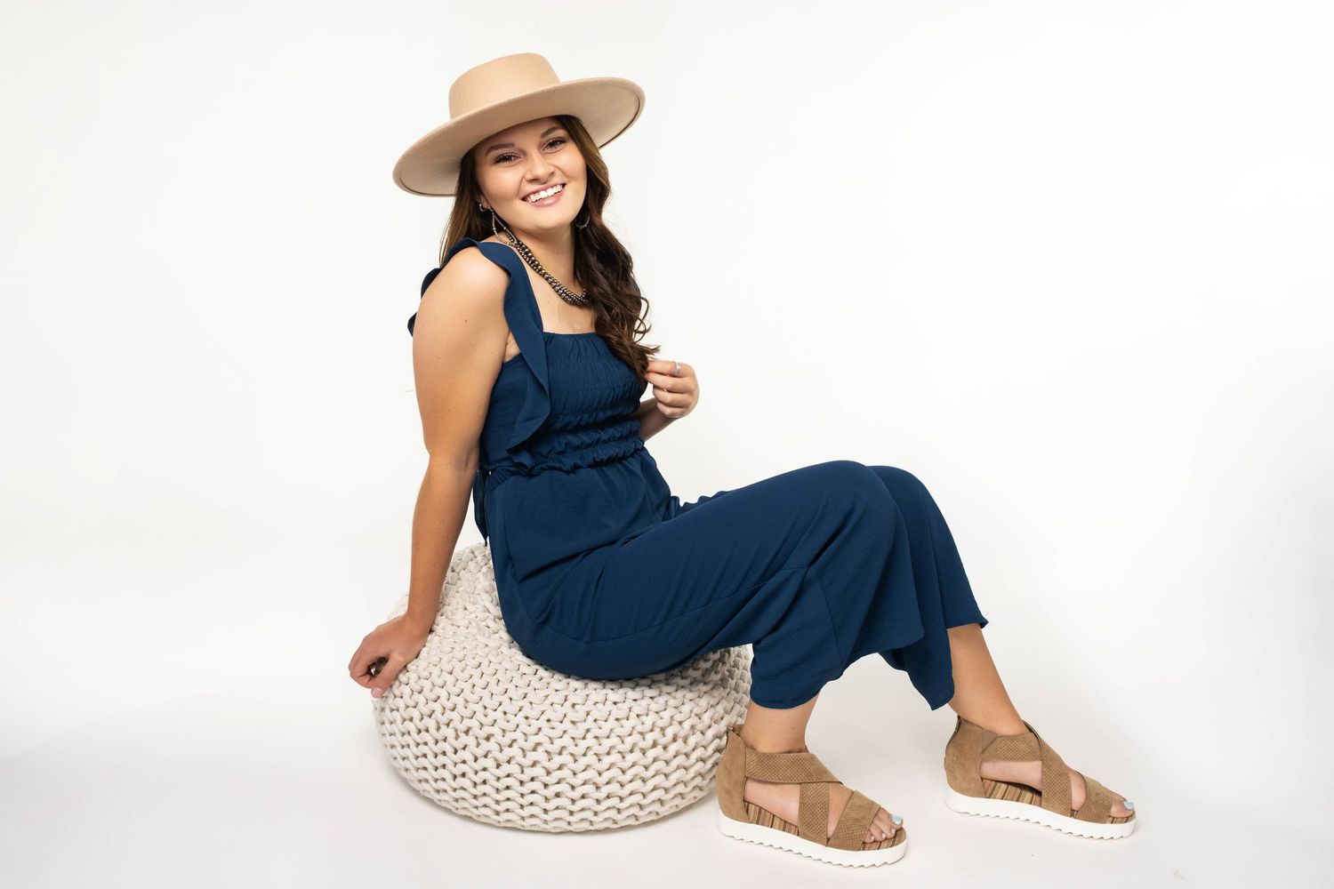 Relaxed lifestyle photos in navy jumpsuit and neutral accessories.