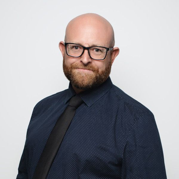 Professional headshots of a person in a dark suit and tie against a white background.