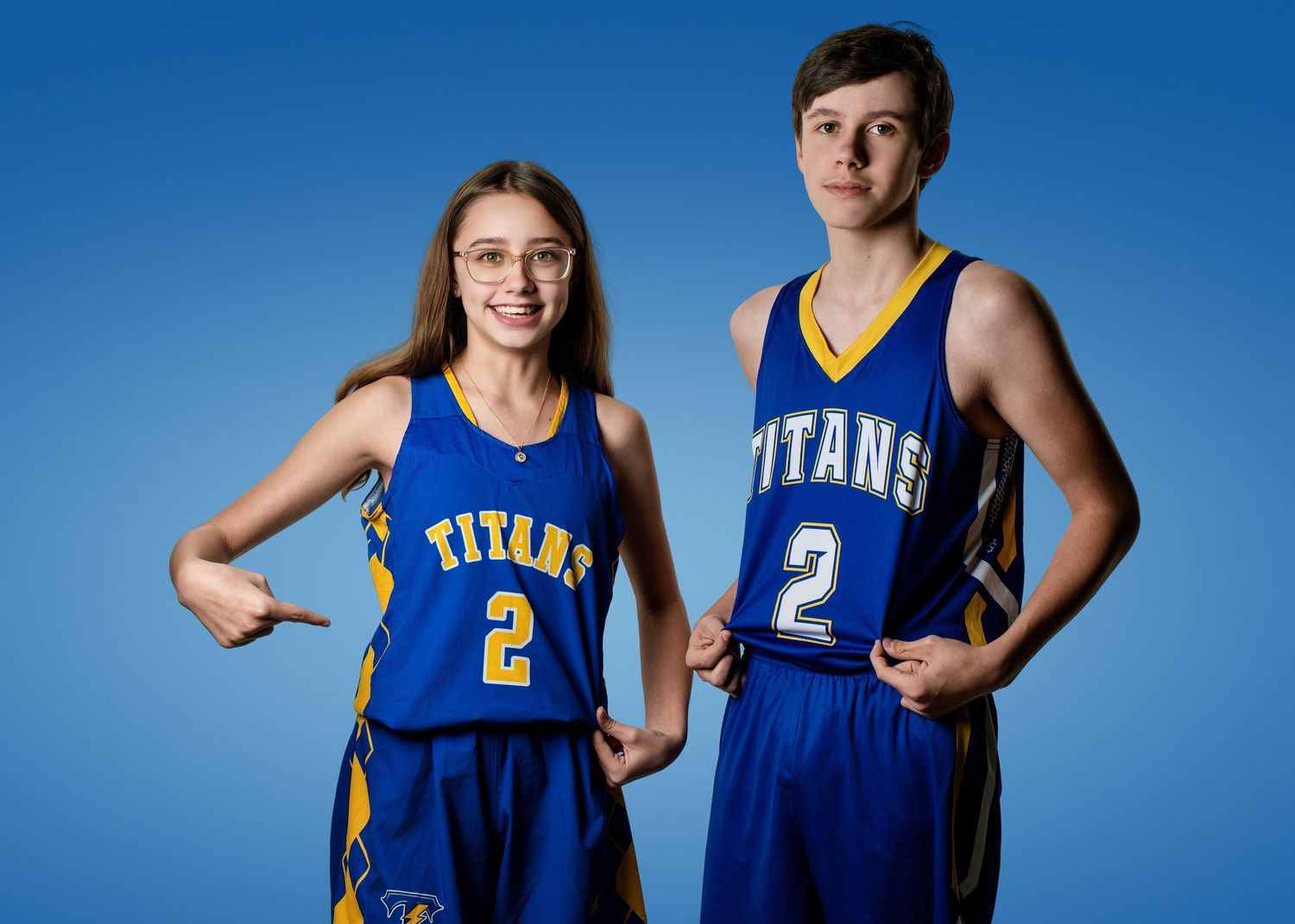 Basketball players pose in blue and gold Titans uniforms against blue backdrop.