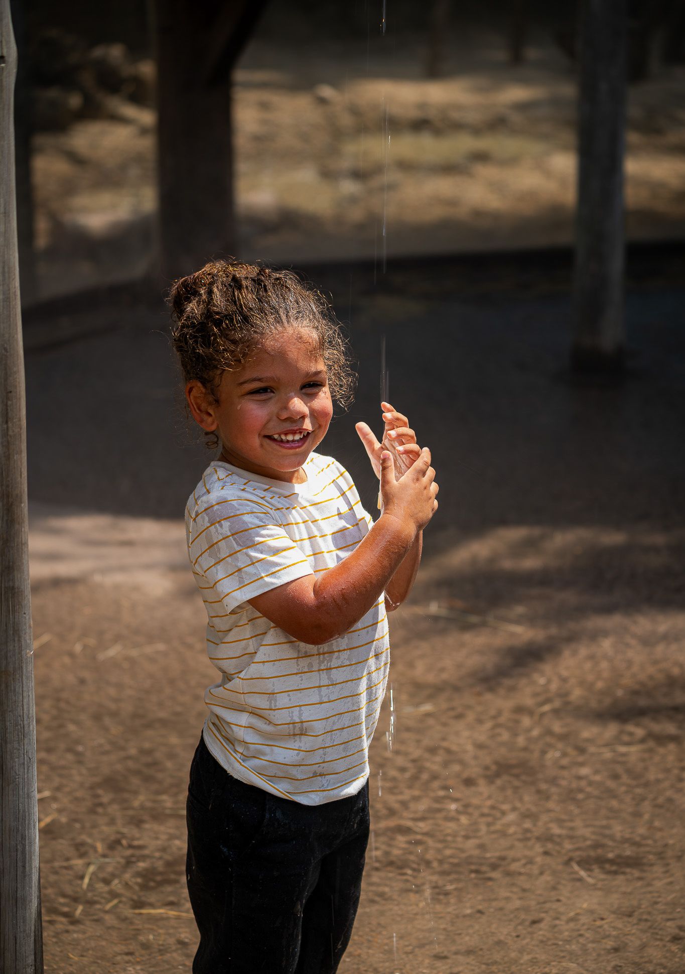 Young child playing outdoors in striped shirt on a sunny day.