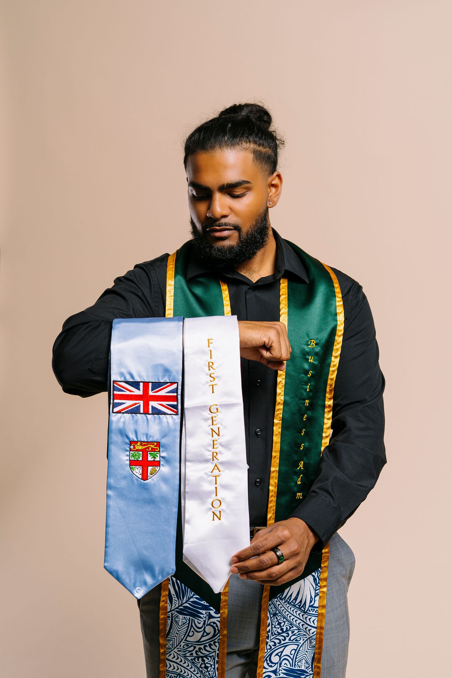 Man holding Fiji flag and First Generation graduation stoles in studio portrait.