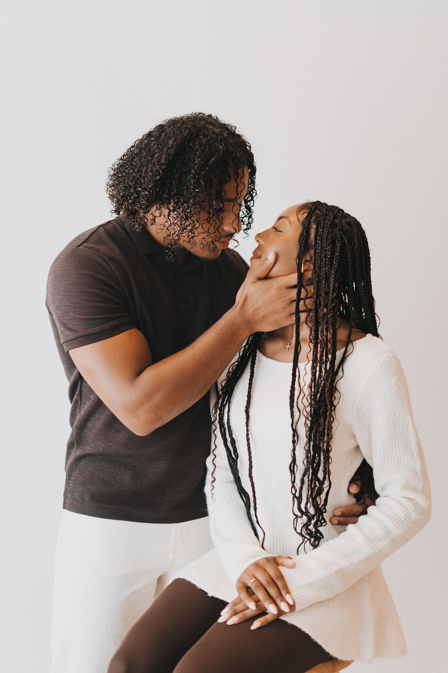 Young Black couple share a tender romantic moment against a light neutral background.